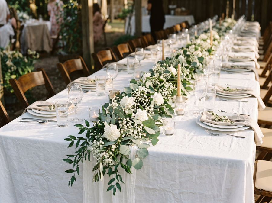 Mesa de celebración con camino de eucalipto, flores blancas y paniculata